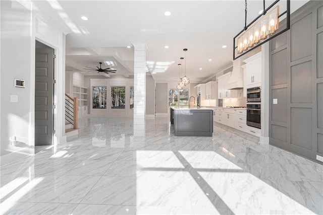 kitchen with marble finish floor, a kitchen island with sink, open floor plan, and recessed lighting
