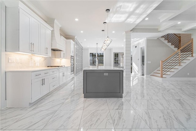 kitchen featuring light countertops, white cabinets, premium range hood, and a kitchen island with sink