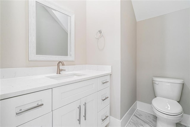 bathroom with marble finish floor, vanity, toilet, and baseboards