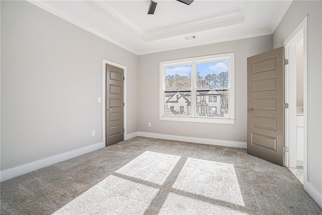 carpeted spare room featuring crown molding, a raised ceiling, visible vents, and baseboards