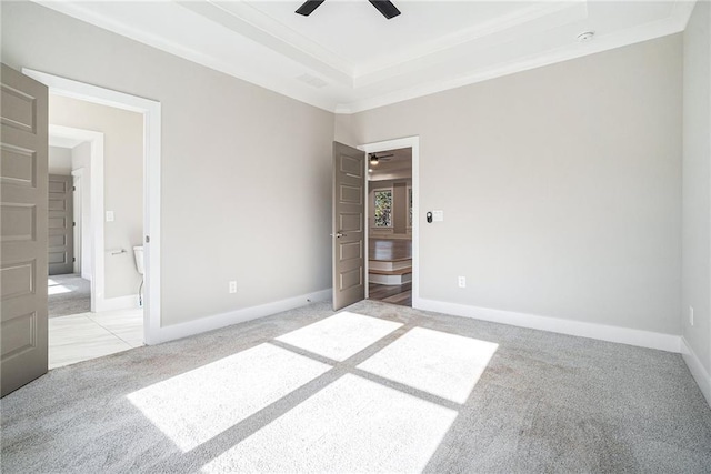 spare room featuring light carpet, visible vents, baseboards, a raised ceiling, and ceiling fan