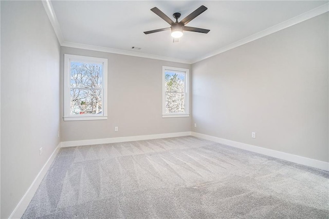 empty room featuring light colored carpet, visible vents, ornamental molding, ceiling fan, and baseboards