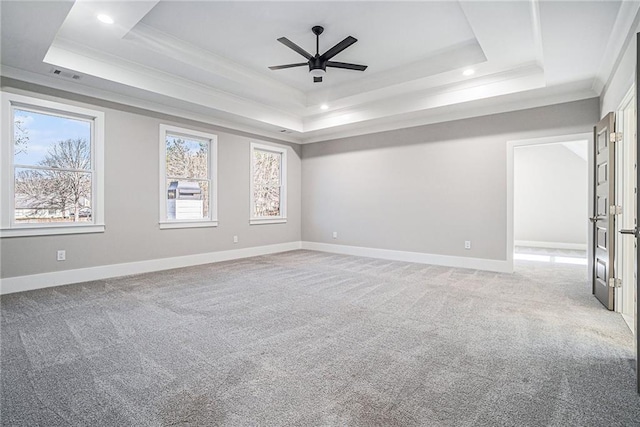 spare room featuring a tray ceiling, light colored carpet, crown molding, and baseboards