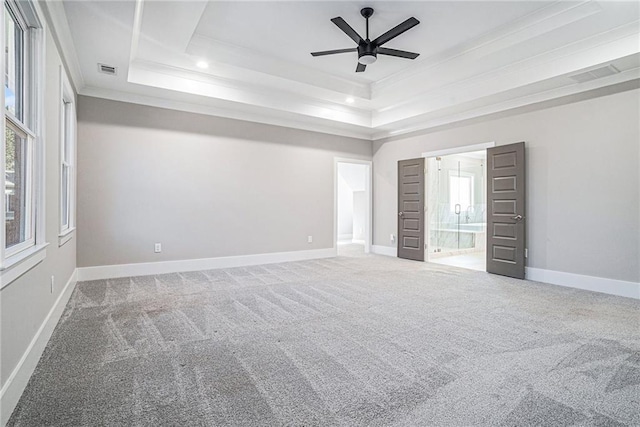 unfurnished bedroom with a tray ceiling, carpet, visible vents, and baseboards