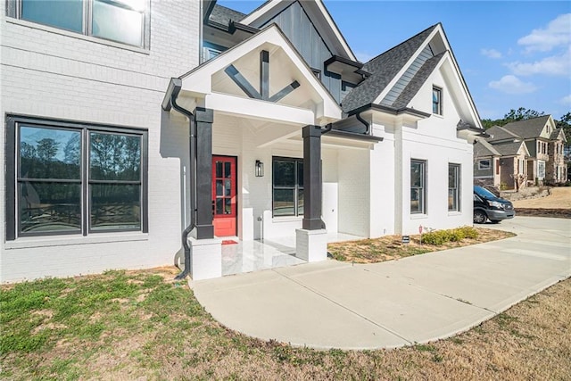 property entrance featuring brick siding and a shingled roof