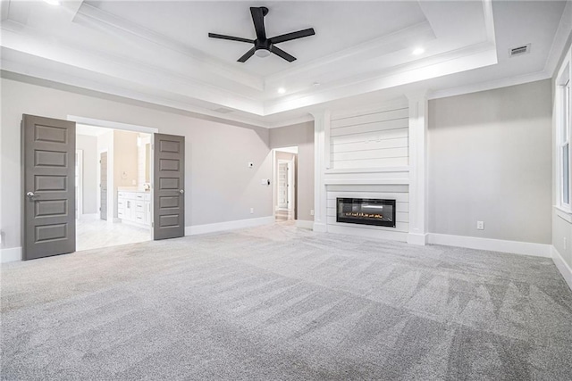 unfurnished living room featuring carpet, baseboards, a raised ceiling, and crown molding