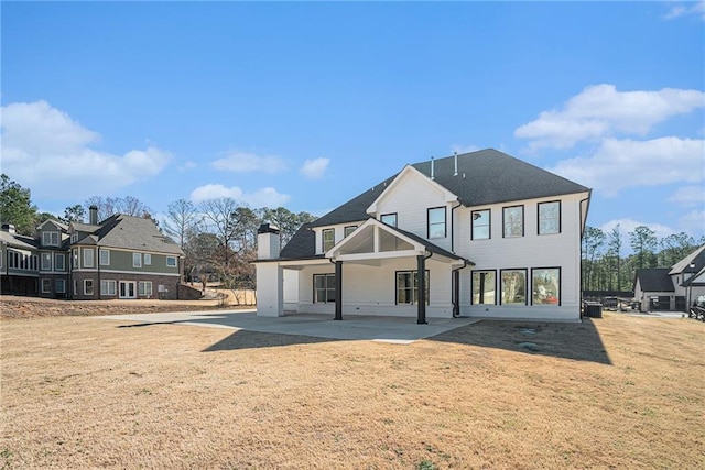 rear view of property with a patio area, a chimney, and a lawn