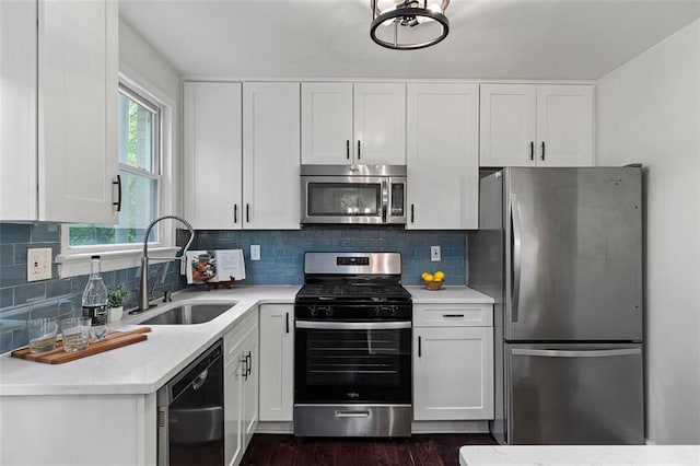 kitchen with appliances with stainless steel finishes, white cabinetry, light countertops, and a sink