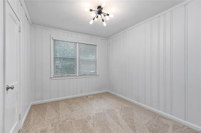 carpeted spare room with visible vents, crown molding, a notable chandelier, and baseboards