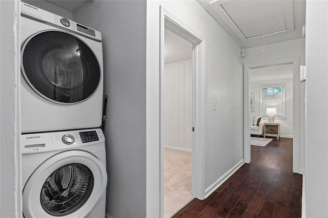 laundry area with stacked washer and dryer, laundry area, attic access, dark wood-style flooring, and baseboards