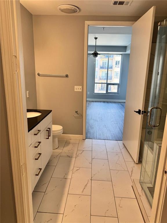 711 Cosmopolitan Dr NE Unit 426, Atlanta, GA 30324 - bathroom featuring marble finish flooring, vanity, toilet, a stall shower, and a ceiling fan