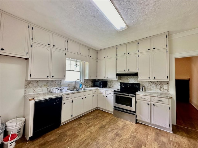 kitchen featuring light hardwood / wood-style floors, white cabinets, a textured ceiling, black appliances, and sink