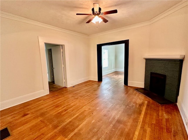 unfurnished living room with ornamental molding, ceiling fan, hardwood / wood-style floors, and a stone fireplace