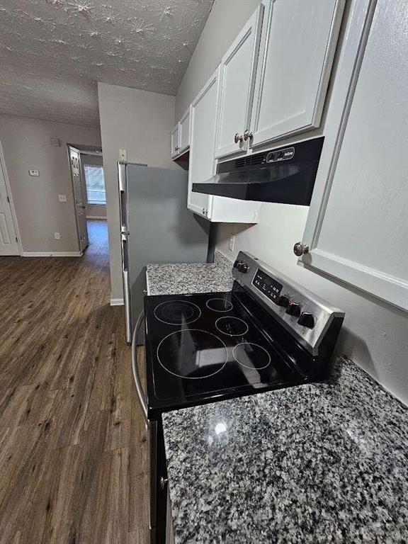 6500 Wellington Chase Ct, Lithonia, GA 30058 - kitchen featuring under cabinet range hood, appliances with stainless steel finishes, white cabinets, a textured ceiling, and dark wood-style flooring