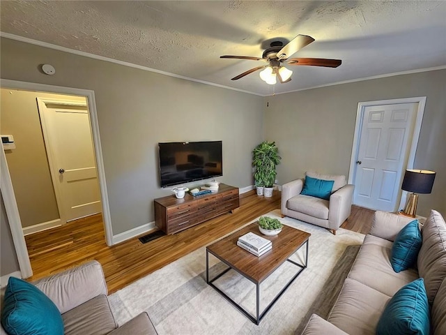 living room with light wood-type flooring, ceiling fan, crown molding, and a textured ceiling