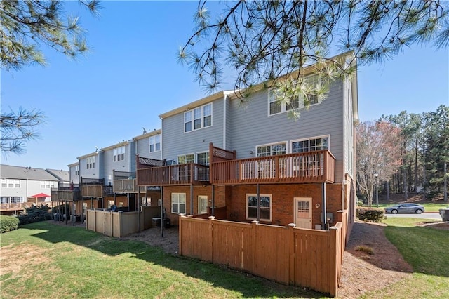 rear view of house with a lawn, a wooden deck, fence, and a residential view