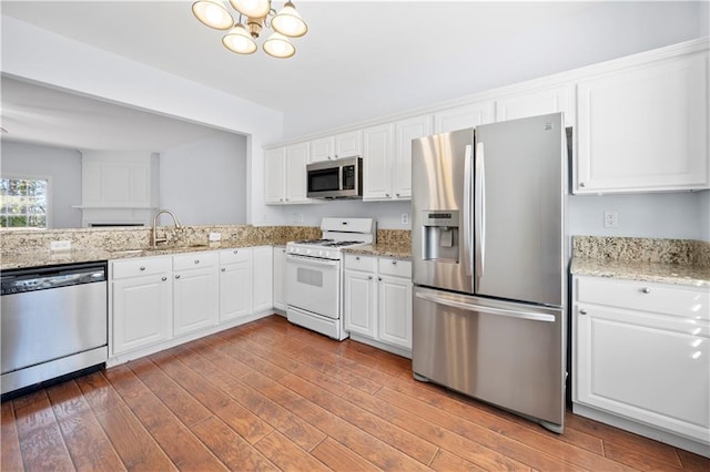 kitchen featuring an inviting chandelier, appliances with stainless steel finishes, a sink, white cabinetry, and light wood-type flooring