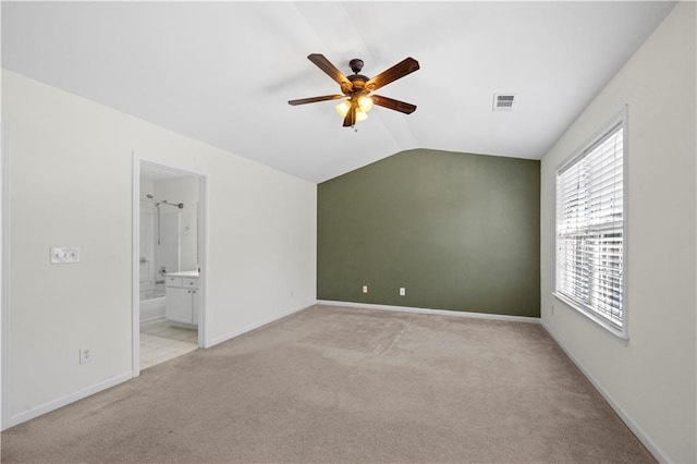 unfurnished bedroom featuring lofted ceiling, light colored carpet, visible vents, baseboards, and ensuite bath