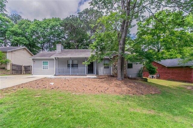 ranch-style house with covered porch, driveway, a chimney, fence, and a front lawn