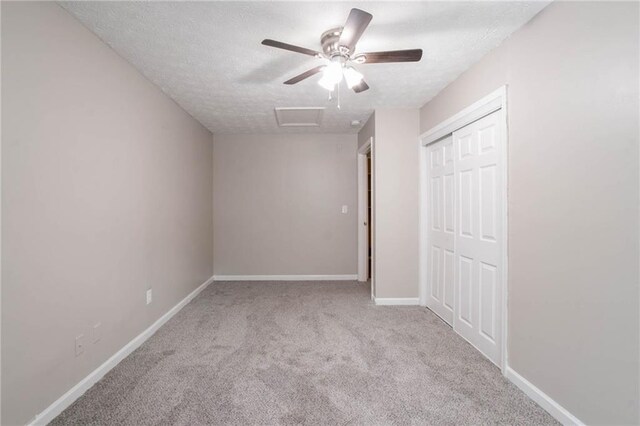 unfurnished bedroom featuring baseboards, carpet, attic access, and a textured ceiling