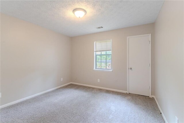 spare room featuring baseboards, carpet, a textured ceiling, and visible vents