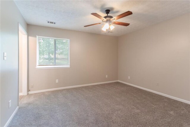 empty room with visible vents, a textured ceiling, carpet, and ceiling fan