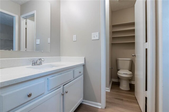 bathroom with vanity, baseboards, wood finished floors, and toilet