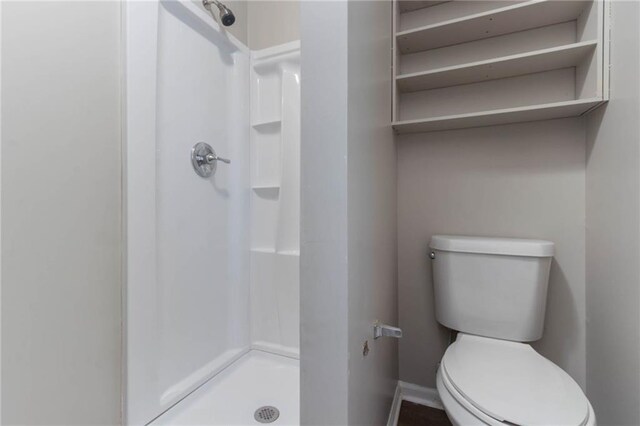 full bath featuring baseboards, a stall shower, and toilet
