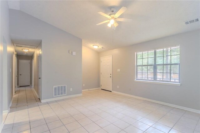 empty room featuring visible vents, light tile patterned floors, and lofted ceiling