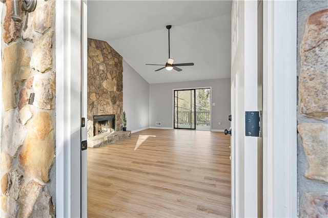 unfurnished living room featuring high vaulted ceiling, a ceiling fan, a fireplace, light wood finished floors, and baseboards