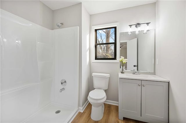 bathroom featuring toilet, walk in shower, wood finished floors, and vanity