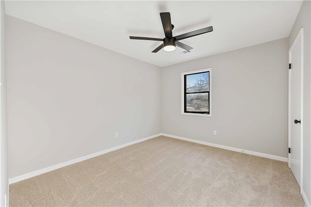 spare room featuring visible vents, light colored carpet, baseboards, and ceiling fan