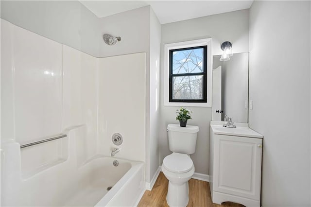 bathroom featuring vanity, wood finished floors, baseboards, toilet, and shower / bathtub combination