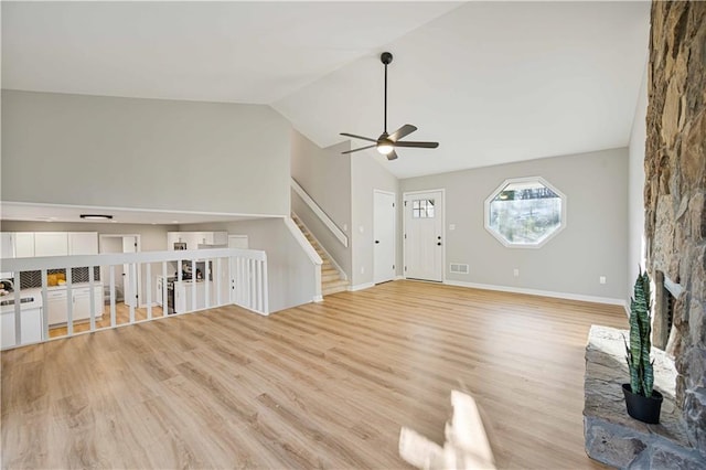 unfurnished living room featuring light wood finished floors, visible vents, lofted ceiling, and a ceiling fan