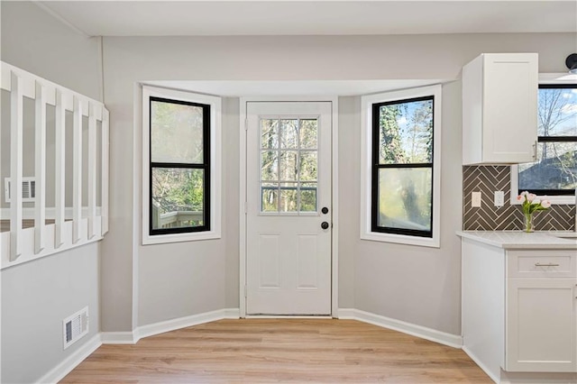 doorway featuring plenty of natural light, light wood-style flooring, and baseboards