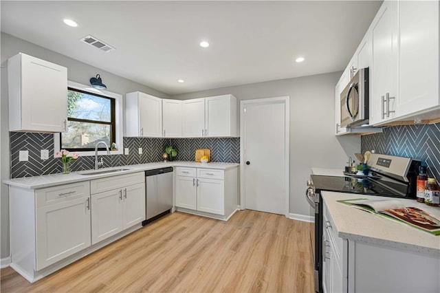 kitchen featuring light wood finished floors, visible vents, appliances with stainless steel finishes, white cabinetry, and a sink