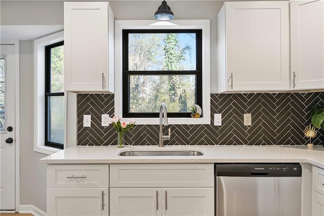 kitchen with a sink, white cabinets, decorative backsplash, light stone countertops, and dishwasher