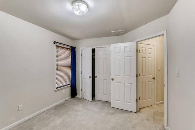 unfurnished bedroom with a closet, light colored carpet, visible vents, and baseboards