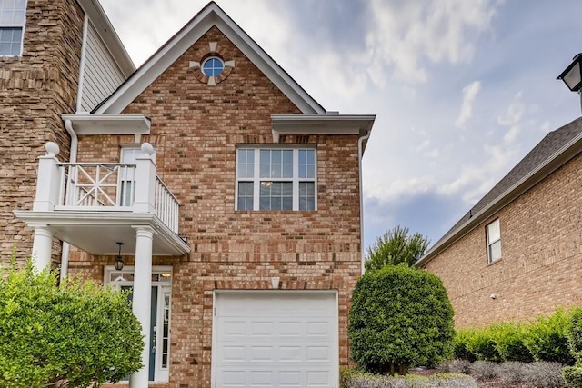 view of front of property with a garage, brick siding, and a balcony