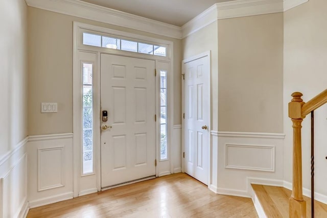 entrance foyer featuring ornamental molding, plenty of natural light, a decorative wall, and light wood finished floors