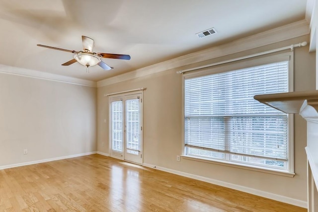 spare room with visible vents, ornamental molding, light wood-style floors, ceiling fan, and baseboards