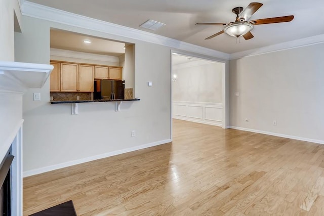 unfurnished living room with visible vents, a ceiling fan, baseboards, ornamental molding, and light wood-type flooring