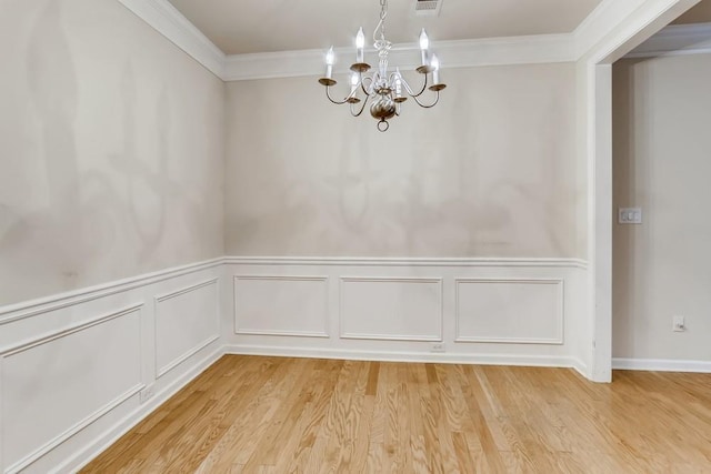 unfurnished dining area featuring ornamental molding, light wood finished floors, and an inviting chandelier