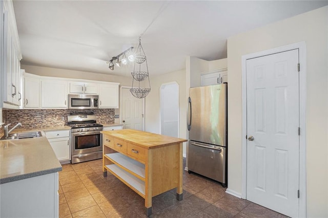 kitchen with sink, white cabinetry, stainless steel appliances, and hanging light fixtures