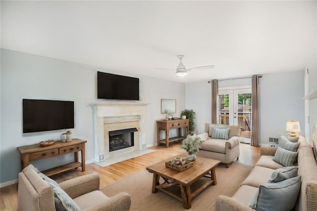 living room with a premium fireplace, french doors, ceiling fan, and light hardwood / wood-style floors