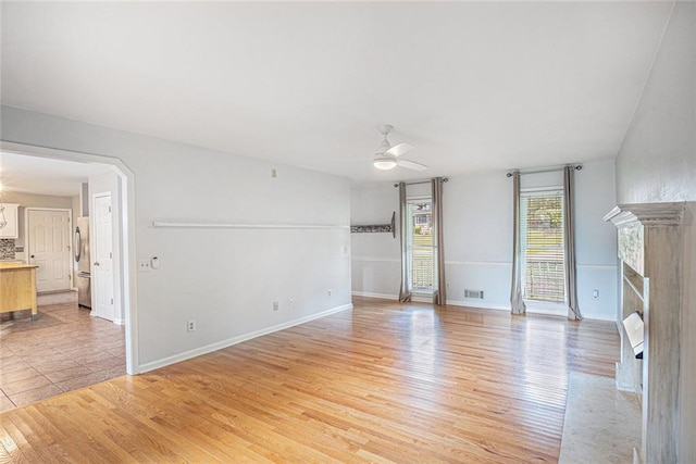 unfurnished living room featuring a fireplace, light hardwood / wood-style flooring, and ceiling fan