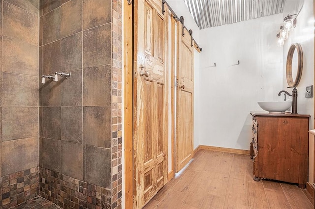 bathroom with a tile shower, hardwood / wood-style floors, and vanity