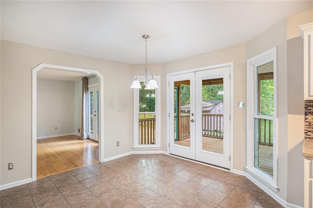 unfurnished dining area with french doors, a notable chandelier, and wood-type flooring