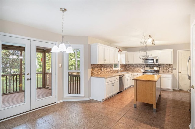 kitchen with pendant lighting, appliances with stainless steel finishes, butcher block countertops, a kitchen island, and white cabinetry