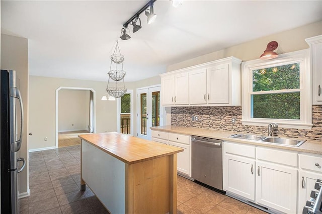 kitchen featuring stainless steel appliances, sink, white cabinetry, a kitchen island, and hanging light fixtures